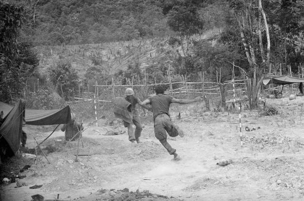 U.S. Marines run to their foxholes as North Vietnamese mortars begin zeroing in on their positions during Operation Hastings near the demilitarized zone between North and South Vietnam on July 17, 1966. (AP Photo/Horst Faas)