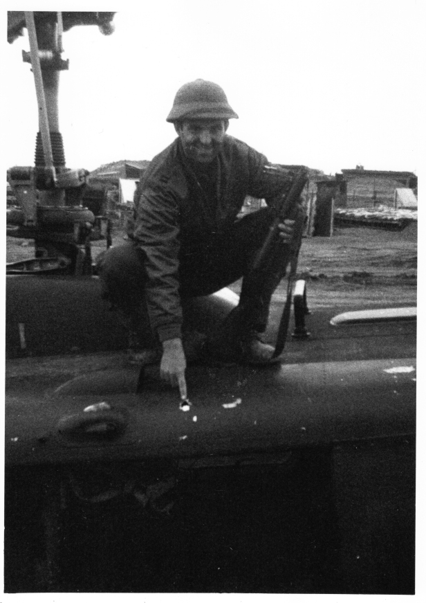The author pointing to one of the bullet holes from the mission noted in this article, while wearing a captured NVA pith helmet and holding his M-79 grenade launcher at LZ Hawk Hill in early January 1970. (Photo courtesy of the author.)